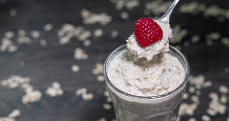 Haferflocken als Overnight Oats mit Himbeere im Glas beim Essen auf Löffel