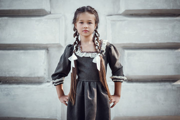 Beautiful little girl in an old dress on the background of the architecture of the historic center