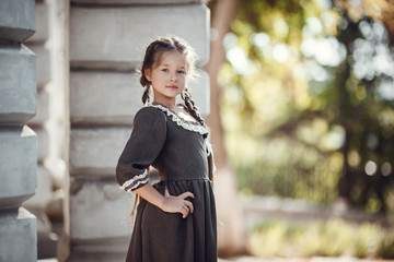 Beautiful little girl in an old dress on the background of the architecture of the historic center
