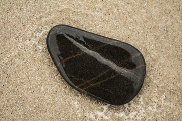 wet black stone on the sand