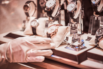 Close-up of the seller's hand in gloves shows the exclusive men's watch from the new collection in...
