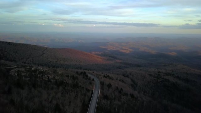 Blue Ridge Parkway in the foreground with mountains at twilight in the background in Avery County North Carolina.
