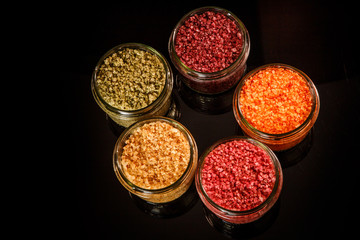top view of small glass jars filled with different colors sea salt