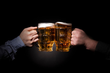 friends toasting with glasses of beer, close up image on dark background