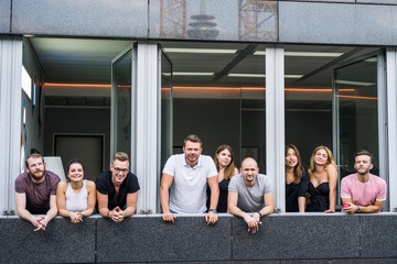 group of young people standing in an office with a large window