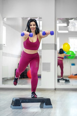 Athletic young girl training with dumbbells in the gym. The concept of sports, a healthy lifestyle,...