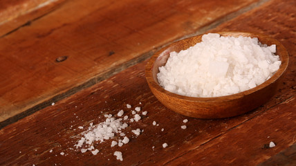 Fototapeta na wymiar Salt or sea salt in a wooden bowl on a aged wooden table background.
