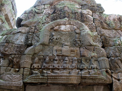 Bas-relief with stone sculptures of Buddha and Apsara dancers in Ta Prohm temple, Angkor, Cambodia