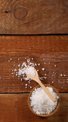 Top view of Salt or sea salt in a wooden bowl on a aged wooden table background.