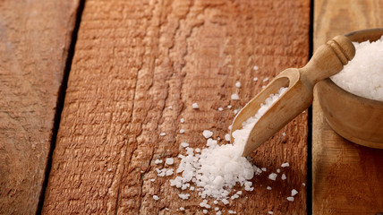 Top view of Salt or sea salt in a wooden bowl on a aged wooden table background.