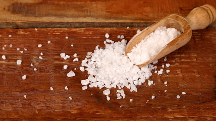 Salt or sea salt in a wooden bowl on a aged wooden table background.
