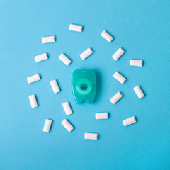 Dental floss and Chewing gum on a blue background. Space for text.