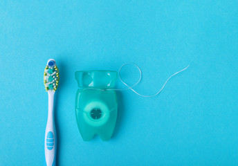 Dental floss and toothbrush on a blue background. Space for text.