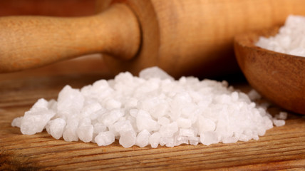 Salt or sea salt and rolling pin on a aged wooden table background.