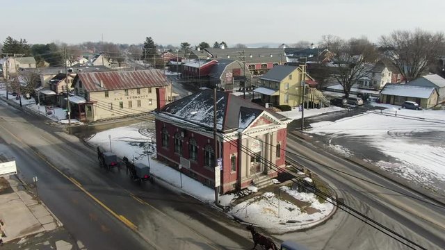 Aerial shot of Amish buggies in town centre. Shot in Intercourse, Pennsylvania in wintertime. A beautiful snow covered rural town with farms, meadows, farmlands and a small village center.