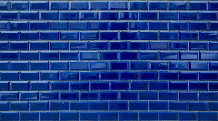 Shiny blue brick tiles on wall. Background texture