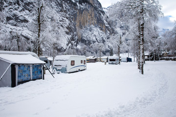 Winter camping with caravan. Camp site in the snow. Camping and travel in Switzerland. Frozen temperatures in the holiday.