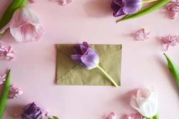 Beautiful floral greeting card for the spring holidays. Delicate pink tulip in a envelope on a pink background. Pastel spring colors. Top view