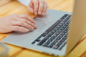 Young women's hands using laptop work. Business lady using a touchpad on a gray laptop.