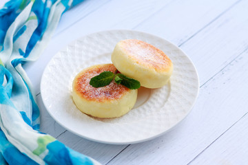 Cheesecake and mint. Cottage cheese pancakes or curd fritters decorated powdered sugar in plate close view. Healthy and diet breakfast.
