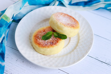 Cottage cheese pancakes or curd fritters decorated powdered sugar in plate close view. Healthy and diet breakfast. Cheesecake and mint.