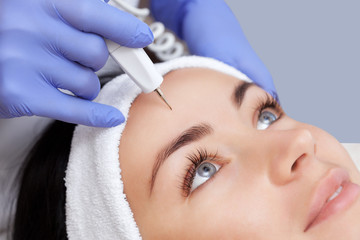 The doctor-cosmetologist makes the procedure treatment of Couperose of the facial skin of a beautiful, young woman in a beauty salon.Cosmetology and professional skin care.