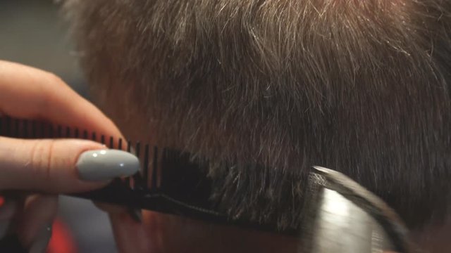 Woman Hairdresser cuts man's hair with electric clipper trimmer. Selective focus