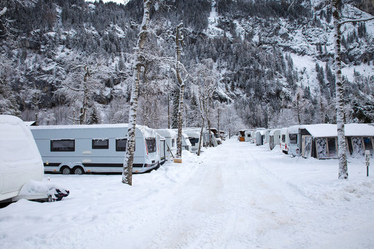 Winter camping with caravan. Camp site in the snow. Camping and travel in Switzerland. Frozen temperatures in the holiday.