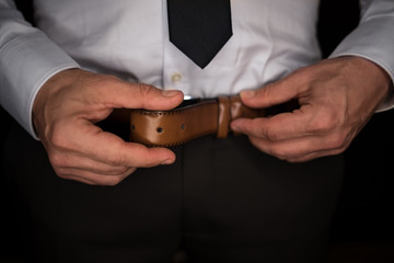 Handsome young man buckling up his belt