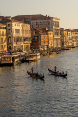 Fototapeta na wymiar Gondolier taking tourists on a Gondola ride along the grand canal near Rialto Hotel in Venice, Italy