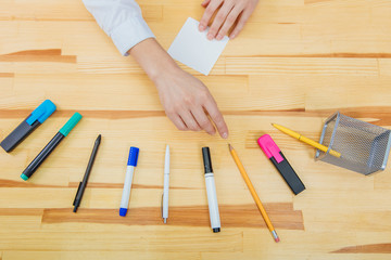 Office table with accessories: a white sheet of paper, a blue-pink marker, a glass of coffee, a feather.