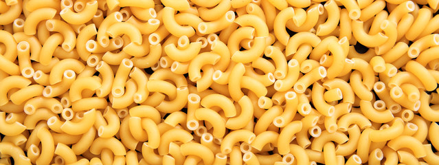 Uncooked macaroni elbow shape pasta texture background, banner