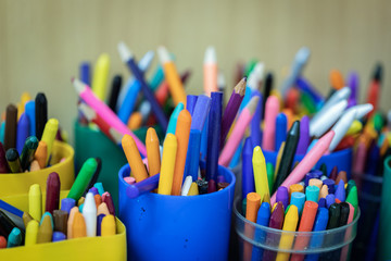 Photo of old brushes for painting, stand in a jar. Children's drawing area, old brushes, on the background of paint and pencils.