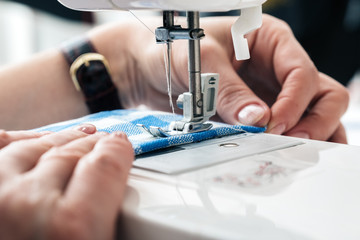 Hands of a woman using a sewing machine in tailor workshop.