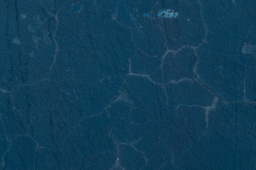 Old, blue painted concrete wall with cracks in plaster and weathering
