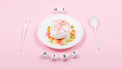 White plate with spoon, fork and Donut decorated icing and sprinkles. Unhealthy Junk Food. Dieting, Healthy Eating, Lifestyle. Weight Loss. Obesity. Minimal style, flat lay, top view