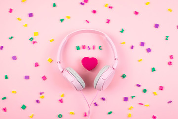 Pink headphones and heart with word MUSIC and multicolored letter symbols on pink background....