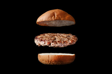 fly burger isolated on black background. bun and meat