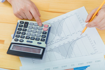 Businesswoman analyzing investment charts with calculator for financial data analyzing counting.