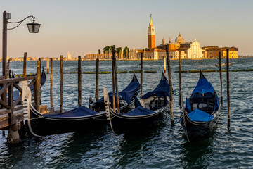 Fototapeta na wymiar Gondolas moored by Saint Mark square with San Giorgio di Maggiore church in the background in Venice, Italy