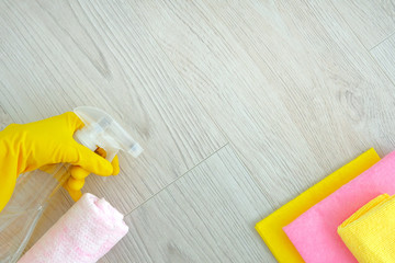 Pink cleaning tools: rags, sponges, detergent liquid, hands in rubber gloves on light wooden background. Detergents and cleaning accessories. Top view.