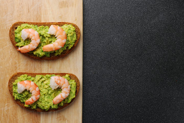 shrimp and guacamole with bread on dark background