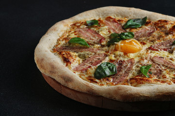 Carbonara pizza with bacon and egg on dark background