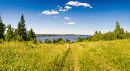 Panoramic view from green hill to Kama river sky with clouds.