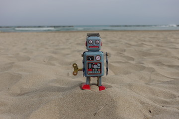 Tin toy retro robot on the beach