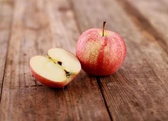 red delicious apples on rustic wooden table - freshly sliced apple pieces - close up