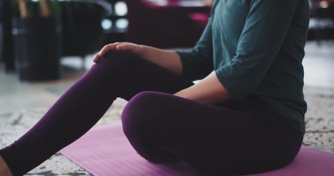 Details stretching body in the morning practicing yoga at home on the mat , in living room wearing comfortable sportswear.