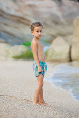 boy standing on the sand by the sea