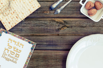 White plate with matzah or matza vintage wood table presented as a Passover seder feast or meal on a rustic vintage background. Translation: Passover Haggadah