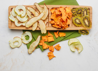 Dried apple, peach, pumpkin and kiwi slices on light marble background